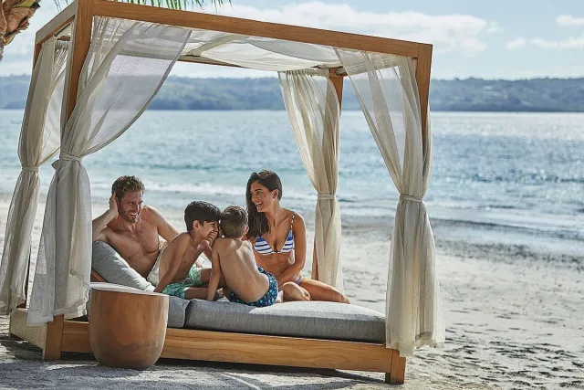 Family of four sharing a beach bed as they relax near the ocean