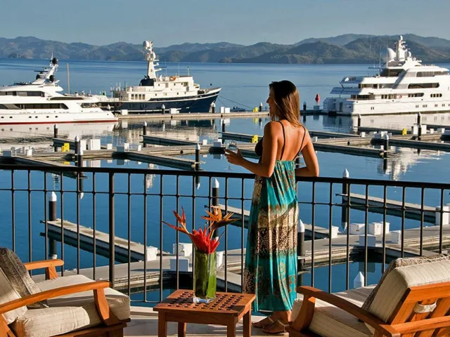 Woman with a dress looking out onto the Marina Papagayo and its docked yatchs in the Papagayo Peninsula, Guanacaste