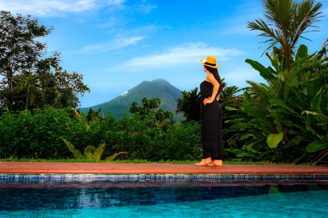 Guest looking at Arenal Volcano in the distance from their hotel pool