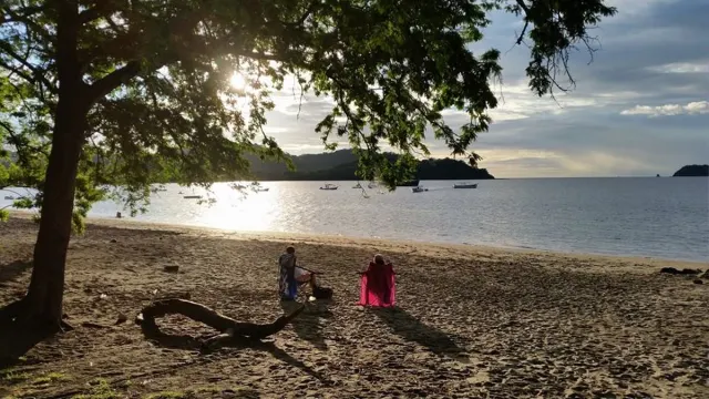 Two people sitting on Playa Panama watching the sunset